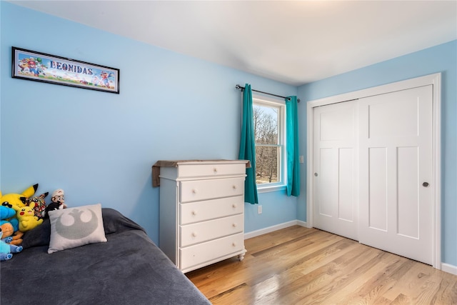 bedroom with light wood-style flooring, baseboards, and a closet