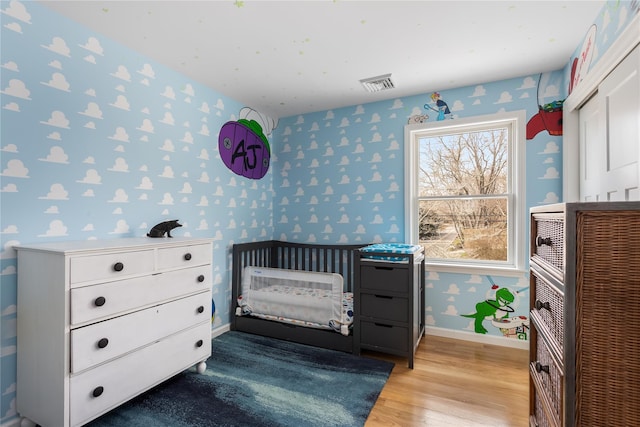 bedroom with wallpapered walls, baseboards, and light wood-style flooring