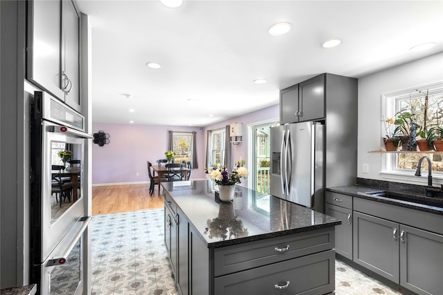 kitchen featuring stainless steel appliances, a sink, gray cabinetry, and recessed lighting