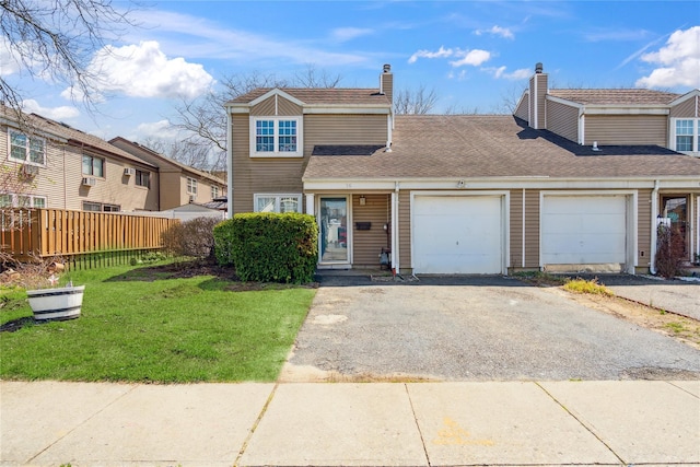 traditional-style house with a chimney, a front lawn, aphalt driveway, fence, and a garage