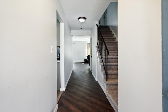 hallway with dark wood-type flooring, baseboards, and stairs