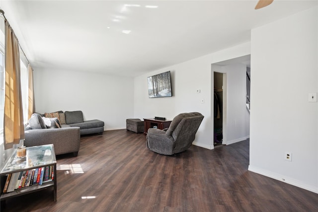 living area featuring wood finished floors, baseboards, and a ceiling fan