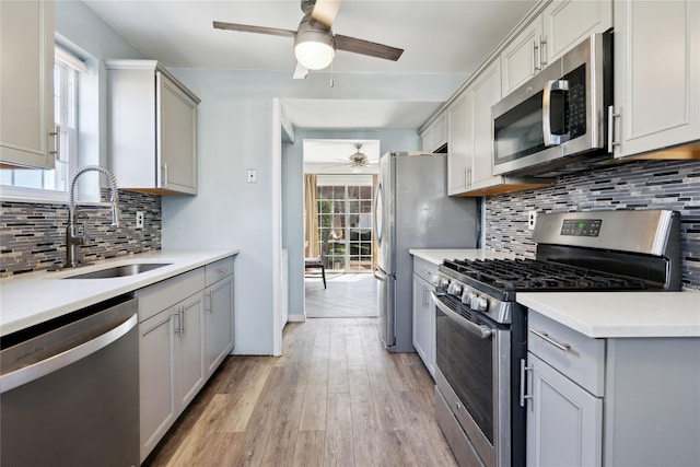 kitchen with ceiling fan, gray cabinets, stainless steel appliances, and a sink
