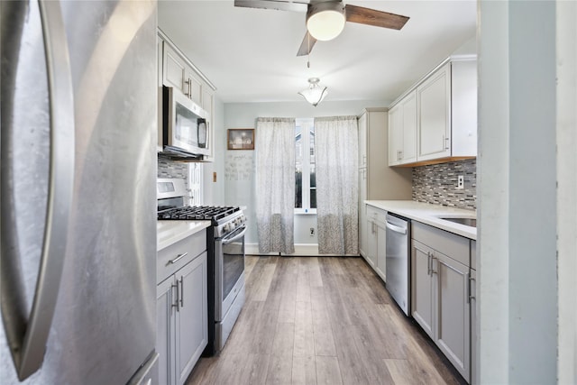 kitchen with decorative backsplash, a ceiling fan, gray cabinets, and stainless steel appliances