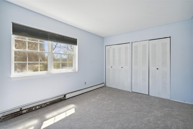 unfurnished bedroom featuring two closets, a baseboard radiator, and carpet