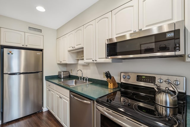 29 Fairway Pl Unit 14, Montauk, NY 11954 - kitchen with white cabinets, dark countertops, appliances with stainless steel finishes, and a sink