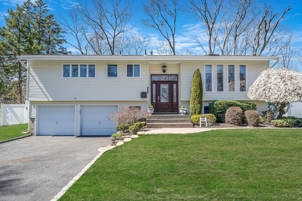 32 Fuller St, Dix Hills, NY 11746 - split foyer home featuring aphalt driveway, fence, an attached garage, and a front yard