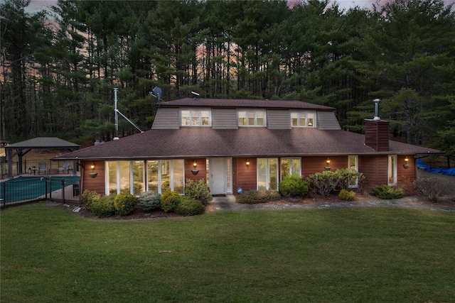 view of front of house with a front yard, a shingled roof, and a chimney