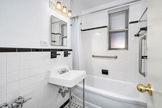 bathroom featuring tile walls, a sink, and shower / tub combo with curtain