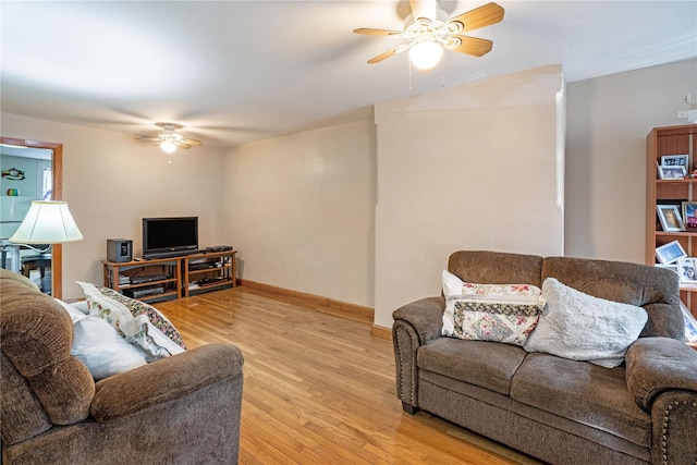 living area with a ceiling fan, baseboards, and light wood-style floors
