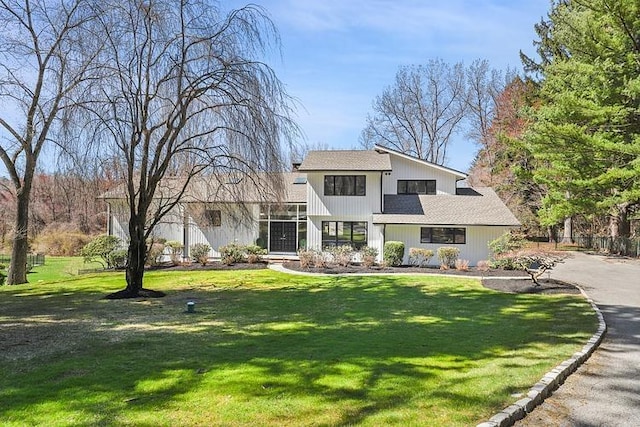 traditional-style house with a shingled roof and a front lawn