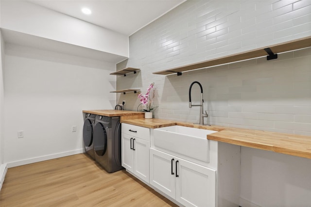 clothes washing area featuring independent washer and dryer, light wood-type flooring, recessed lighting, a sink, and baseboards