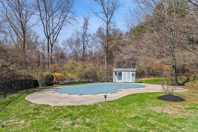view of pool with an outdoor structure, a covered pool, a yard, fence, and a storage unit