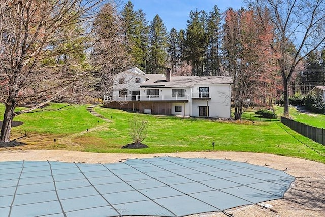 rear view of property featuring stairway, a lawn, fence, a covered pool, and a deck