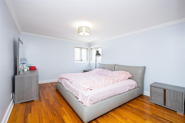 bedroom with baseboards, wood finished floors, and ornamental molding