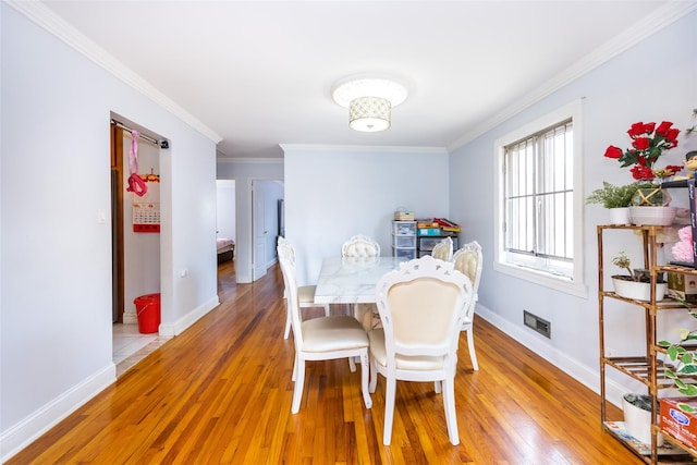 dining space with baseboards, ornamental molding, and light wood-type flooring