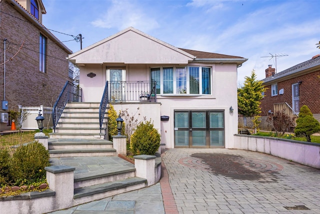 view of front of house featuring stucco siding, a patio, and stairway