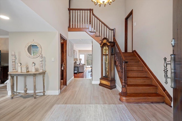 foyer with baseboards, a high ceiling, wood finished floors, and stairway