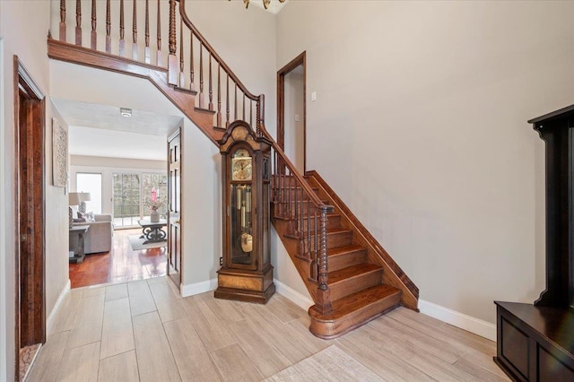 stairs featuring a high ceiling, baseboards, and wood finished floors
