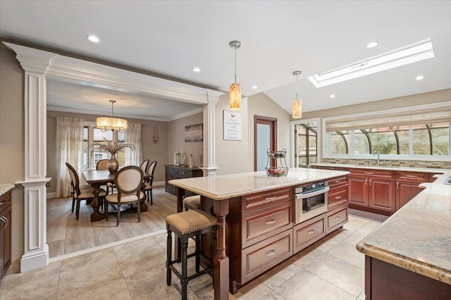 kitchen featuring a kitchen bar, stainless steel oven, a chandelier, a sink, and light stone counters