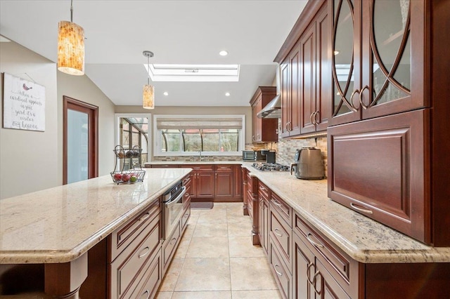 kitchen featuring decorative backsplash, glass insert cabinets, light stone countertops, and wall chimney exhaust hood