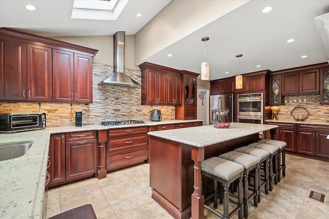 kitchen featuring a toaster, stainless steel appliances, a kitchen island, glass insert cabinets, and wall chimney range hood
