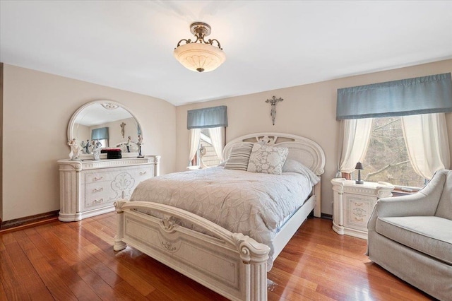 bedroom with baseboards, light wood-style flooring, and multiple windows