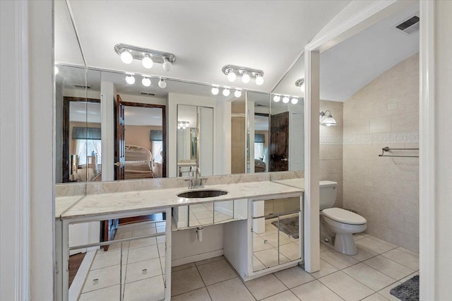 full bathroom with toilet, vanity, tile patterned flooring, ensuite bath, and tile walls
