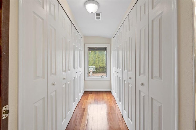hallway with baseboards, visible vents, and light wood-type flooring