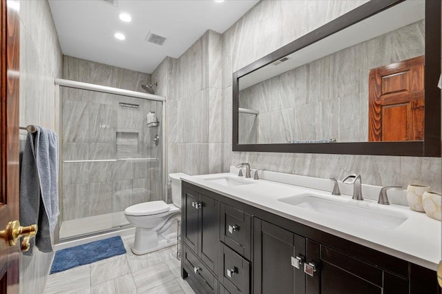 bathroom with tile walls, a sink, toilet, and a shower stall