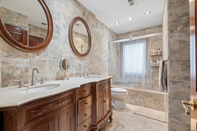 bathroom featuring a sink, tiled shower / bath, tile walls, and visible vents