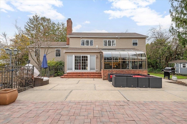 rear view of house with a chimney, entry steps, a sunroom, and a patio area
