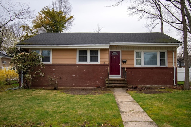 view of front of property featuring a shingled roof, brick siding, a chimney, and a front lawn