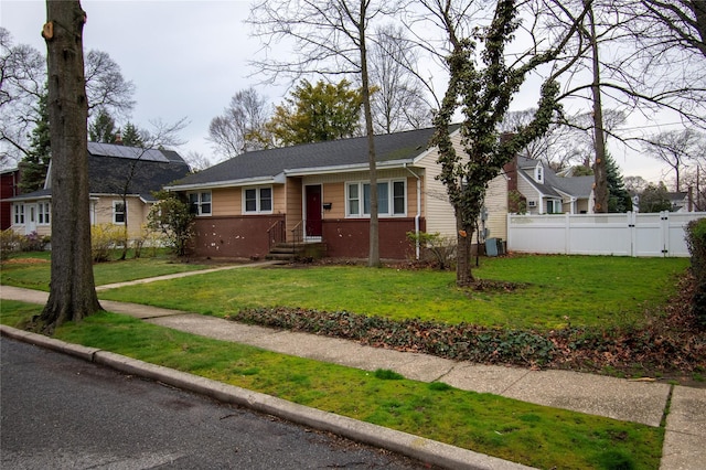 bungalow-style house with fence, a front lawn, and brick siding