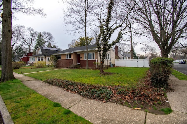 view of front facade featuring a front yard, fence, and brick siding
