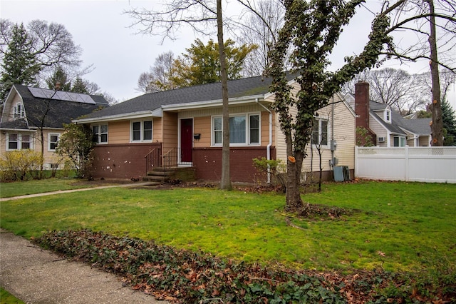 view of front of property with a front yard, fence, and brick siding