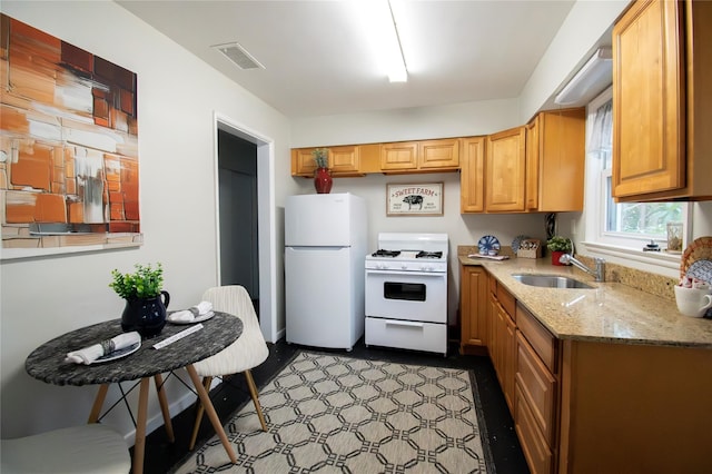 kitchen with white appliances, visible vents, a sink, and light stone counters