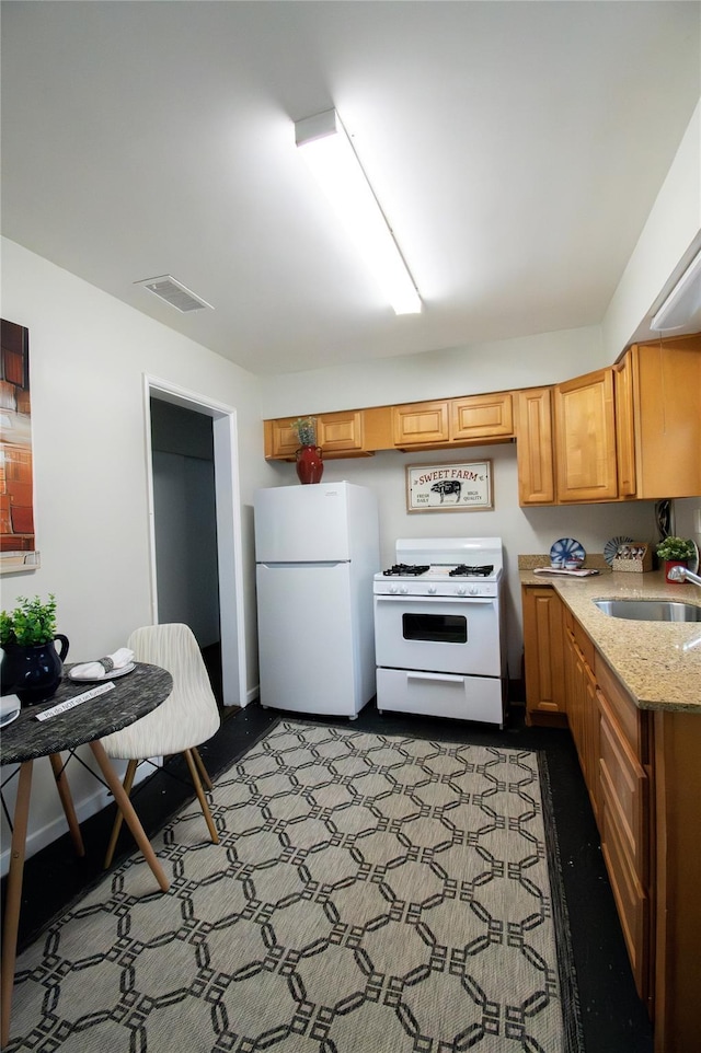 kitchen featuring a sink, visible vents, white appliances, and light stone counters