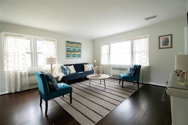 living room with wood finished floors, baseboards, ornamental molding, and visible vents