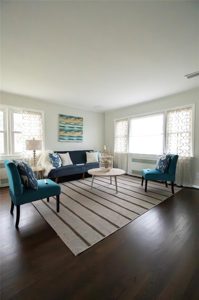 living area featuring visible vents, radiator heating unit, and wood finished floors