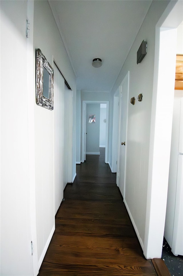 corridor with baseboards and dark wood finished floors