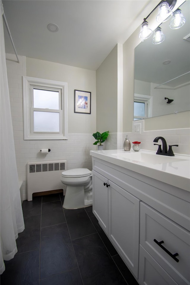 bathroom with toilet, tile walls, radiator, and a healthy amount of sunlight