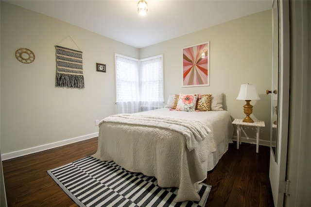 bedroom with dark wood-style flooring and baseboards
