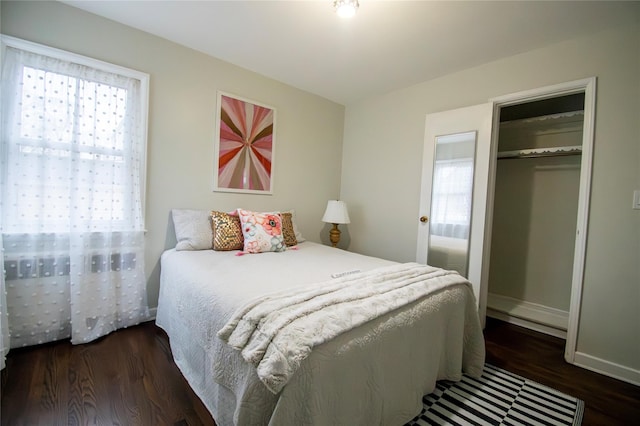 bedroom with wood finished floors, a closet, baseboards, and multiple windows