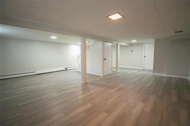 finished below grade area featuring a baseboard heating unit, recessed lighting, baseboards, and wood finished floors