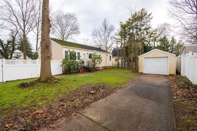 view of yard with fence, an outdoor structure, a garage, and aphalt driveway