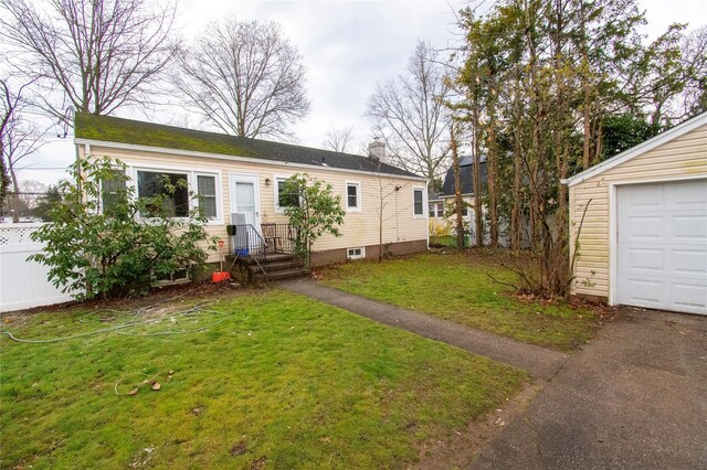 view of front facade with driveway, a garage, a front yard, and fence
