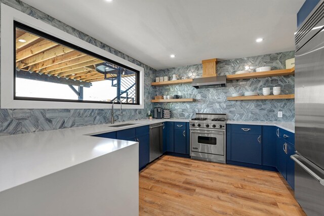1166 Hastings Cir, Baldwin Harbor, NY 11510 - kitchen with high end appliances, blue cabinets, wall chimney exhaust hood, open shelves, and light countertops