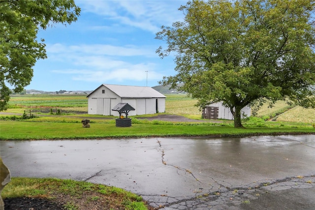 exterior space with an outdoor structure, a pole building, a rural view, and a detached garage