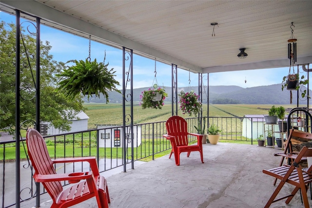 sunroom / solarium featuring concrete floors, a mountain view, and a rural view